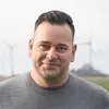 Portraitfoto des Geschäftsführers Christian Hammerthaler von Pro New Energy mit Windkraftanlagen im Hintergrund